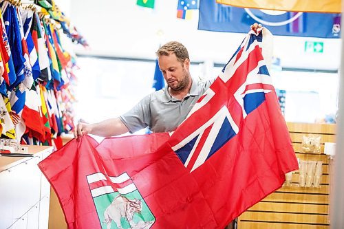 MIKAELA MACKENZIE / WINNIPEG FREE PRESS
	
Mathew Hobson, a sales associate at The Flag Shop on Osborne, shows the current Manitoba flag on Monday, Aug. 19, 2024. According to a Probe Research poll, 49% of Manitobans would support creating a new flag for the province.

Winnipeg Free Press 2024