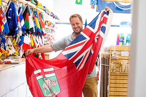 MIKAELA MACKENZIE / WINNIPEG FREE PRESS
	
Mathew Hobson, a sales associate at The Flag Shop on Osborne, shows the current Manitoba flag on Monday, Aug. 19, 2024. According to a Probe Research poll, 49% of Manitobans would support creating a new flag for the province.

Winnipeg Free Press 2024