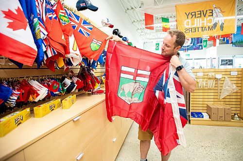 MIKAELA MACKENZIE / WINNIPEG FREE PRESS
	
Mathew Hobson, a sales associate at The Flag Shop on Osborne, shows the current Manitoba flag on Monday, Aug. 19, 2024. According to a Probe Research poll, 49% of Manitobans would support creating a new flag for the province.

Winnipeg Free Press 2024