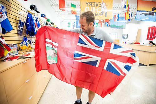 MIKAELA MACKENZIE / WINNIPEG FREE PRESS
	
Mathew Hobson, a sales associate at The Flag Shop on Osborne, shows the current Manitoba flag on Monday, Aug. 19, 2024. According to a Probe Research poll, 49% of Manitobans would support creating a new flag for the province.

Winnipeg Free Press 2024