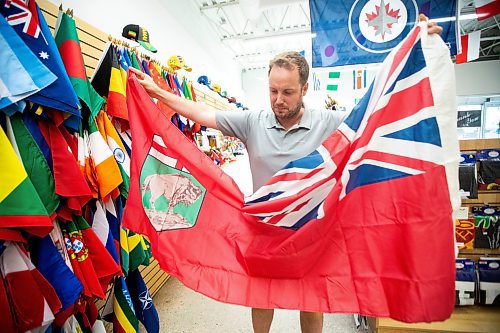 MIKAELA MACKENZIE / WINNIPEG FREE PRESS
	
Mathew Hobson, a sales associate at The Flag Shop on Osborne, shows the current Manitoba flag on Monday, Aug. 19, 2024. According to a Probe Research poll, 49% of Manitobans would support creating a new flag for the province.

Winnipeg Free Press 2024