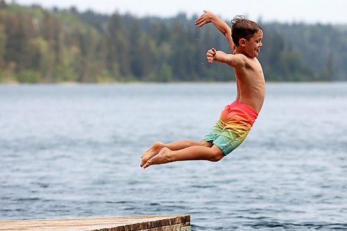 Bennett Davies of Brandon leaps off the dock into Clear Lake at Deep Bay in Riding Mountain National Park on an overcast and hot Tuesday afternoon. (Tim Smith/The Brandon Sun)