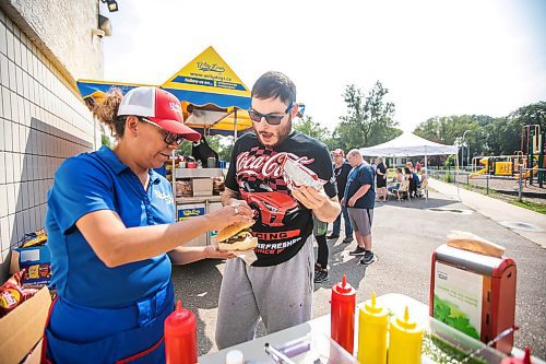 MIKAELA MACKENZIE / WINNIPEG FREE PRESS
	
Jody Smart (left) helps Johnny Grant with his burger toppings at the DASCH Inc. and DASCH Foundation 50th anniversary barbecue at the Norwood Community Centre on Tuesday, Aug. 20, 2024.

Winnipeg Free Press 2024