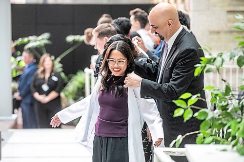 MIKAELA MACKENZIE / WINNIPEG FREE PRESS
	
WRHA CEO Mike Nader cloaks Allison Afable in the white-coat ceremony for the newest University of Manitoba medical class at the Max Rady College of Medicine on Wednesday, Aug. 21, 2024.

For Jura story.
Winnipeg Free Press 2024