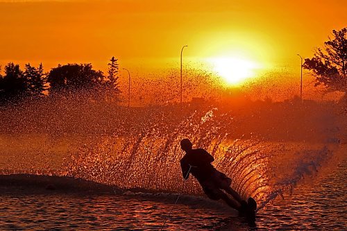 Herman Lepp with the Brandon Waterski Club kicks up a wall of spray while slalom skiing on the Assiniboine River in Brandon as the sun rises over the horizon early Wednesday morning. (Tim Smith/The Brandon Sun)