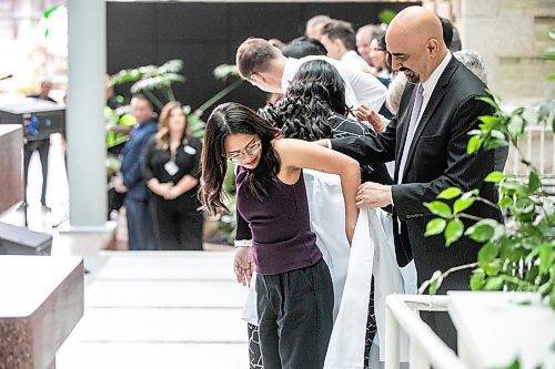 MIKAELA MACKENZIE / WINNIPEG FREE PRESS
	
WRHA CEO Mike Nader cloaks Allison Afable in the white-coat ceremony for the newest University of Manitoba medical class at the Max Rady College of Medicine on Wednesday, Aug. 21, 2024.

For Jura story.
Winnipeg Free Press 2024