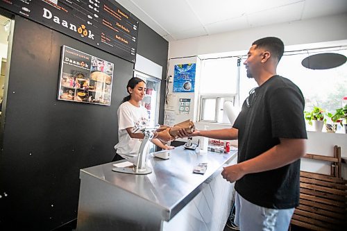 MIKAELA MACKENZIE / WINNIPEG FREE PRESS
	
Naz Kahil hands Josh Mendoza his beef sharwarma wrap at Danook Restaurant on Friday, Aug. 23, 2024. The Syrian establishment has a tipping prompt, which helps staff; the restaurant can't afford to pay staff higher wages without raising its menu prices, the owner said. 

For Gabby story.
Winnipeg Free Press 2024