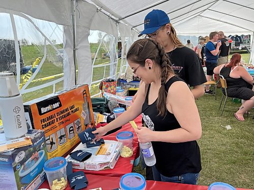 Kelsey Parisien and Brent Titchkosky make their selections in the silent auction during the 11th annual fundraising barbeque for Special Olympics, hosted by Murray and Heather Manuliak at the Brandon Riverbank Discovery Centre on Saturday. (Michele McDougall/The Brandon Sun)
