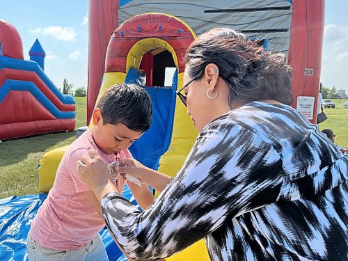 Five year old Alex Milla's mom puts a sticker on his shirt that was given to him by Brandon Police Service Saturday afternoon during the 11th annual fundraising barbeque for Special Olympics, hosted by Murray and Heather Manuliak at the Brandon Riverbank Discovery Centre. (Michele McDougall/The Brandon Sun)