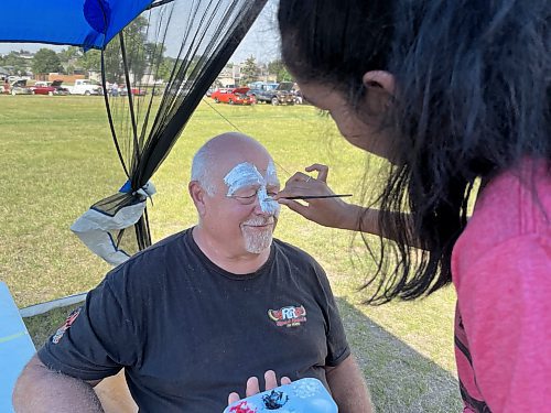 Dave Burba, president of the Road Rebels Car Club gets his face painted by Krisha Patel Saturday afternoon during the 11th annual fundraising barbeque for Special Olympics, hosted by Murray and Heather Manuliak at the Brandon Riverbank Discovery Centre. (Michele McDougall/The Brandon Sun)