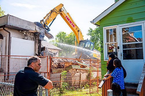 NIC ADAM / FREE PRESS
Neighbours Kenny Costa, Angel and Michael Williams and Samantha Newton (from left) watch as a crew demolishes the vacant house along Manitoba Ave. that burned down due to multiple fires in a few short months. According to the land-owner, the city approved his months-old demolition permit after the release of our last article on the subject.
240826 - Monday, August 26, 2024.

Reporter: Malak