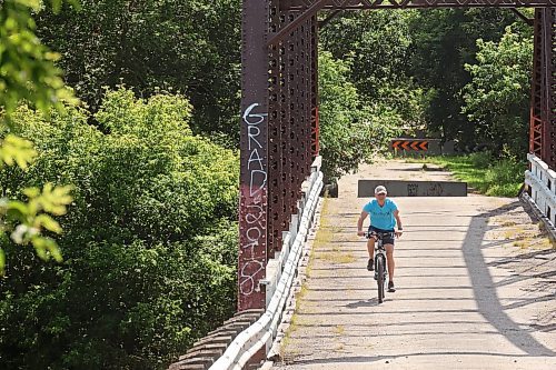 27082024
A cyclist makes their way across the steel through truss bridge, which has long been closed to vehicle traffic, in Wawanesa on a warm Tuesday afternoon. 
(Tim Smith/The Brandon Sun)