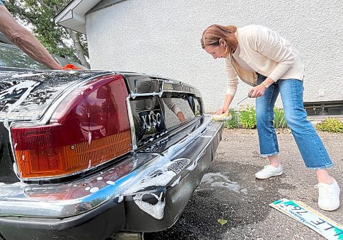 Darlene Hildebrand hand washes the chrome bumper of Steve Van Vlaenderen's 1988 Jaguar XJS convertible, V-12 Thursday afternoon in Brandon. (Michele McDougall/The Brandon Sun)
