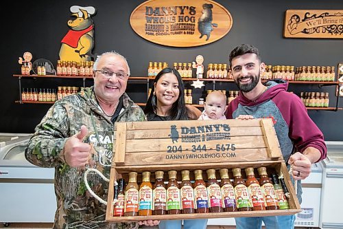 BROOK JONES ./ FREE PRESS
Danny Kleinsasser, 62, (left) of Danny's Whole Hog Barbecue &amp; Smokehouse is pictured with his son Isaiah Kleinsasser, 25, his daughter-in-law Kaeziah Kleinsasser, 24, and his granddaughter seven-month-old Ariyah Kleinsasser. Kleinsasser and his family are pictured holding various bottled flavours of Danny's Own Barbecue Sauce at the family's retail store at 12045 PTH 67 in the RM of Rockwood, Man., Thursday, Aug. 29, 2024.