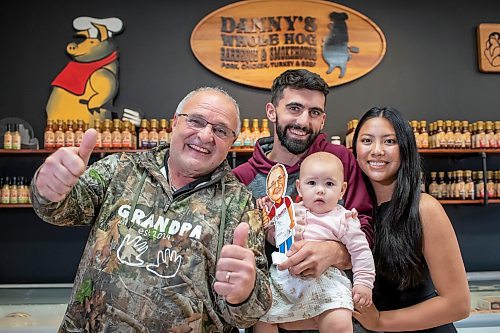 BROOK JONES ./ FREE PRESS
Danny Kleinsasser, 62, (left) of Danny's Whole Hog Barbecue &amp; Smokehouse gives two thumbs up as he is pictured with his son Isaiah Kleinsasser, 25, his daughter-in-law Kaeziah Kleinsasser, 24, and his granddaughter seven-month-old Ariyah Kleinsasser. Kleinsasser and his family are pictured at the family's retail store at 12045 PTH 67 in the RM of Rockwood, Man., Thursday, Aug. 29, 2024.