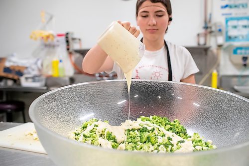 BROOK JONES ./ FREE PRESS
Cassidy Kleinsasser, 14, who is the youngest daughter of Danny Kleinsasser of Danny's Whole Hog Barbecue &amp; Smokehouse is pictured adding caesar dressing to a broccoli and cauliflower salade at the family's operation at 12045 PTH 67 in the RM of Rockwood, Man., Thursday, Aug. 29, 2024.