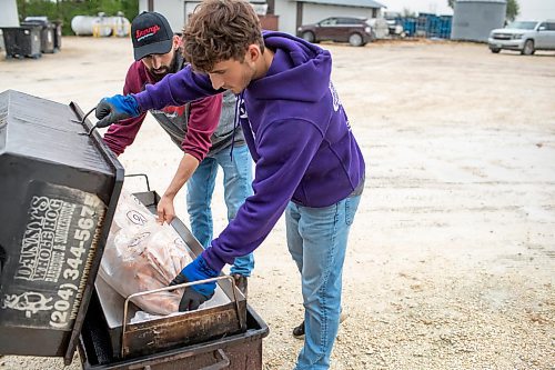 BROOK JONES ./ FREE PRESS
Ezra Kleinsasser, 18, (right) and his brother Isaiah Kleinsasser, 25, load a hog onto a do it yourself cooker. The brothers are the son's of Danny Kleinsasser of Danny's Whole Hog Barbecue &amp; Smokehouse and are pictured at the family's operation at 12045 PTH 67 in the RM of Rockwood, Man., Thursday, Aug. 29, 2024.