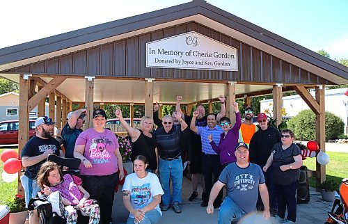 Brandon’s Ken Gordon (centre, wearing a dark shirt and blue jeans) waves along with several participants of COR Enterprises Inc. on Friday afternoon during the grand opening of a new open-air gazebo that was recently built built beside COR's main building with his $90,000 donation. (Michele McDougall/The Brandon Sun)
