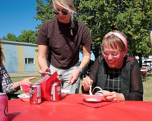 Tannis Figol, a participant at COR Enterprises Inc. in Brandon, smiles as she enjoys a piece of cake during the grand opening of a new open-air gazebo that was recently built beside COR's main building. (Michele McDougall/The Brandon Sun)