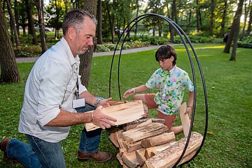 BROOK JONES / FREE PRESS
Firewood Manitoba owner Clint Vieira (left) and his 10-year-old son place firewood in a outdoor rack at A Picnic in Provence - Garden Party 2024 at the Leo Mol Sculpture Garden at Assiniboine Park in Winnipeg, Man., Wednesday, Aug. 28, 2024. The annual fundraiser supports the Assiniboine Park Conservancy and this year's event included 500 guests.