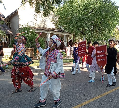 Parade participants wearing colourful traditional costumes and carrying banners march down Eighth Street. (John Gleeson/The Brandon Sun)