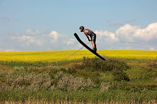 31072024
A crop of canola in bloom blankets the prairie bordering the small lake/pond as ski jumper Casey Mommer trains in late July. Mommer has been jumping as much as possible this summer, when the wind is right. Most sessions consist of two sets of three or four jumps, which is about as much as Mommer&#x2019;s feet can take in the incredibly tight bindings. 
(Tim Smith/The Brandon Sun)