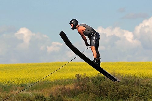 31072024
A crop of canola in bloom blankets the prairie bordering the small lake/pond as ski jumper Casey Mommer trains in late July. Mommer has been jumping as much as possible this summer, when the wind is right. Most sessions consist of two sets of three or four jumps, which is about as much as Mommer&#x2019;s feet can take in the incredibly tight bindings. 
(Tim Smith/The Brandon Sun)