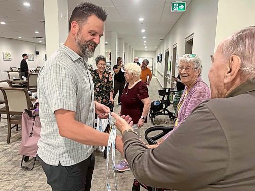 Ian Trembath shows his two gold medals and shakes hands with a resident of Rotary Villas at Crocus Gardens on Tuesday morning. (Michele McDougall/The Brandon Sun)