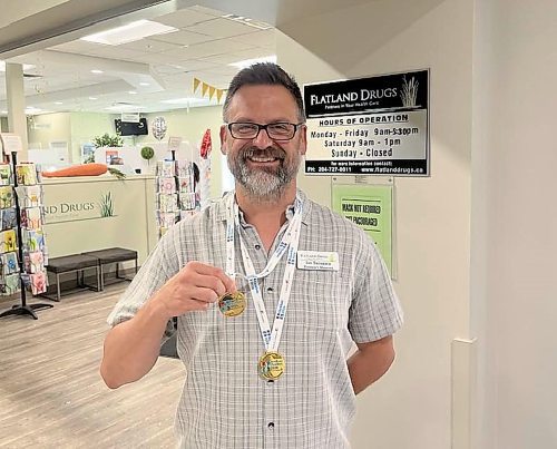 Trembath stands outside his business, Flatland Pharmacy, and shows the two gold medals he won in swimming at the 2024 Canada 55+ Games in Quebec. (Michele McDougall/The Brandon Sun)