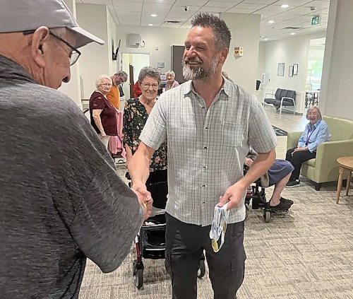 Ian Trembath talks and shakes hands with a resident of Rotary Villas at Crocus Gardens as he shows his two gold medals he won for swimming at the 2024 Canada 55+ Games in Quebec for the 100-metre and 50-metre freestyle — or front crawl races. (Michele McDougall/The Brandon Sun)