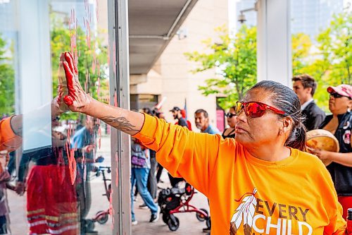 NIC ADAM / FREE PRESS
Irene Bear paints a red handprint on the WPS headquarters after shutting down the intersection at Portage and Main early Wednesday afternoon after Tammy Bateman, an Indigenous woman, was struck and killed by a police vehicle at a homeless encampment.
240904 - Wednesday, September 04, 2024.

Reporter: Nicole