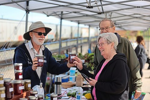 Left: O'Soleil Produce owner Leo Demers (left) sells bottles of jam to Linda Day and husband Rick at the Downtown Summer Market on Friday afternoon. Demers lauds the market's organization and convenient setup. "It's an exceptional market to be at," he said. (Abiola Odutola/The Brandon Sun)