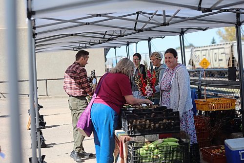 Right: Mandy Brandt, Hannah Peters, and Dana Plett attend to customers buying vegetables from their farm at the Downtown Summer Market Friday afternoon. (Abiola Odutola/The Brandon Sun)