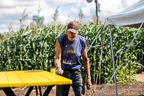 Sven Conquist paints tables at the Field of Dreams baseball diamond near Clearwater, Manitoba on Thursday. (Mikaela MacKenzie/Winnipeg Free Press)