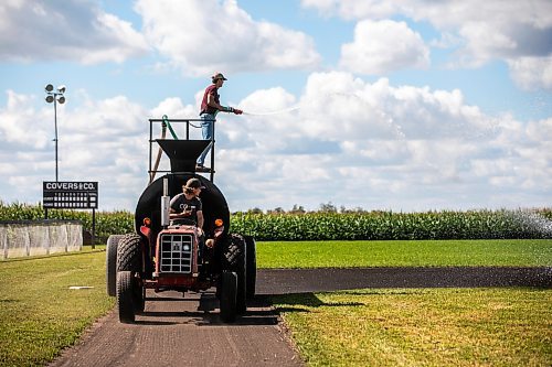 MIKAELA MACKENZIE / WINNIPEG FREE PRESS

Joe Gardiner drives the tractor as Jace Guilford waters the infield at the Field of Dreams baseball diamond near Clearwater, Manitoba on Thursday, Sept. 5, 2024. 

For Mike McIntyre story.
Winnipeg Free Press 2024