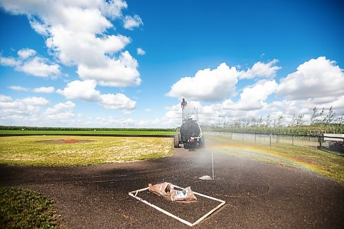 MIKAELA MACKENZIE / WINNIPEG FREE PRESS

A rainbow forms over home plate as Jace Guilford waters the infield at the Field of Dreams baseball diamond near Clearwater, Manitoba on Thursday, Sept. 5, 2024. 

For Mike McIntyre story.
Winnipeg Free Press 2024