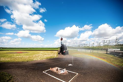 MIKAELA MACKENZIE / WINNIPEG FREE PRESS

A rainbow forms over home plate as Jace Guilford waters the infield at the Field of Dreams baseball diamond near Clearwater, Manitoba on Thursday, Sept. 5, 2024. 

For Mike McIntyre story.
Winnipeg Free Press 2024