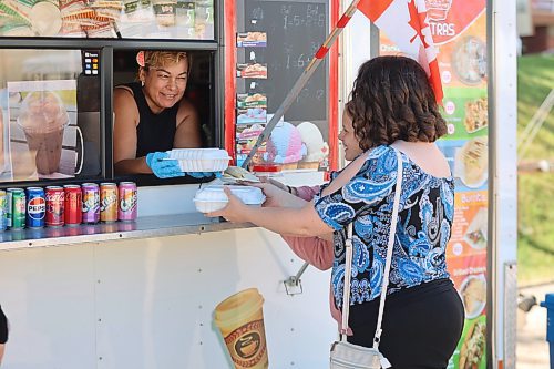 Left; Delicious Catrachos owner Sadia Pereiai sells food to Olivia Loewen, and her mother, Ruth, from her truck at the Downtown Summer Market Friday afternoon. (Abiola Odutola/The Brandon Sun)