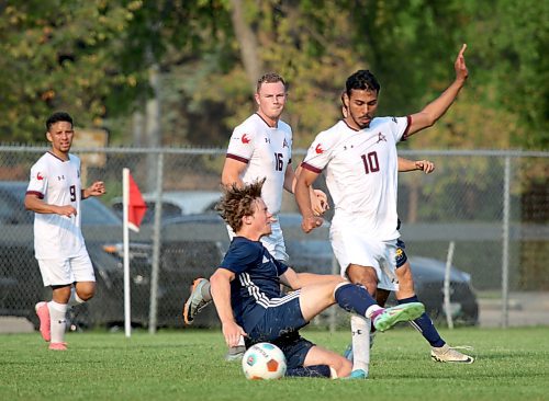 Brandon's Carter Wiebe tackles AC's Paulo Pinto at knee height, earning a yellow card as former Bobcat Stefan McGonigle (16) looks on. (Thomas Friesen/The Brandon Sun)