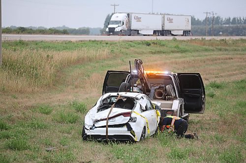 A tow truck operator from Carberry works to hoist a car with Ontario plates after the vehicle rolled and came to a stop in the northwest ditch of the Trans-Canada Highway and Highway 5 intersection early Thursday morning. (Matt Goerzen/The Brandon Sun)