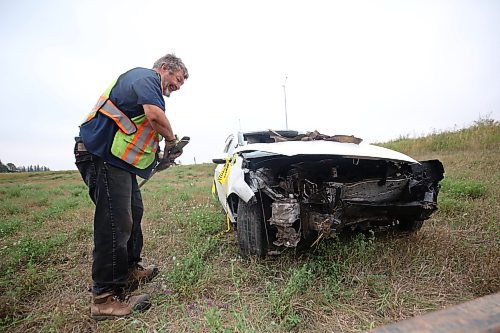 A tow truck operator from Carberry works to hoist a car with Ontario plates after the westbound vehicle had left the road, flipped end over end and came to a stop in the northwest ditch of the Highway 5 and Trans-Canada Highway early Thursday morning. Emergency crews had to take the roof off of the car to reach the driver, who was taken away from the scene by ambulance. (Matt Goerzen/The Brandon Sun)