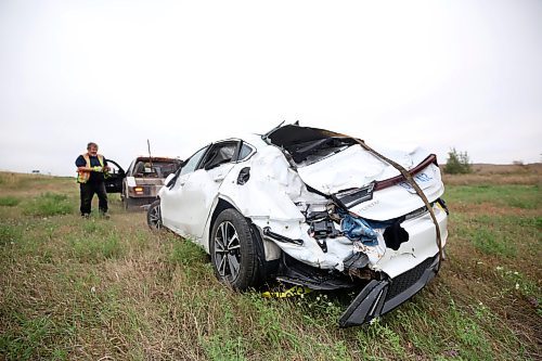 A tow truck operator from Carberry works to hoist a car with Ontario plates after the westbound vehicle had left the road, flipped end over end and came to a stop in the northwest ditch of the Highway 5 and Trans-Canada Highway early Thursday morning. Emergency crews had to take the roof off of the car to reach the driver, who was taken away from the scene by ambulance. (Matt Goerzen/The Brandon Sun)