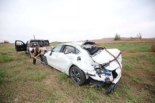 A tow truck operator from Carberry works to hoist a car with Ontario plates after the westbound vehicle had left the road, flipped end over end and came to a stop in the northwest ditch of the Highway 5 and Trans-Canada Highway early Thursday morning. Emergency crews had to take the roof off of the car to reach the driver, who was taken away from the scene by ambulance. (Matt Goerzen/The Brandon Sun)