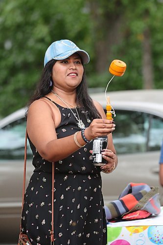 Vashi Teepsoo, originally from Mauritius, tries her hand at coca — also known as a valero pop — during the community barbecue. (Matt Goerzen/The Brandon Sun)