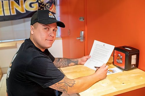 BROOK JONES / FREE PRESS
Winnipegger Eric Saniuk, 30, who is the owner of Blazing Chicken Shack reads over a waiver (thought it's not actually a legal requirment) he'll have customers sign for fun before they eat an extremely hot sandwhich which is coming to his menu soon. Saniuk was pictured at his restaurant at 392 Graham Ave., in Winnipeg, Man., Monday, Sept. 16, 2024.