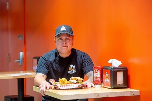 BROOK JONES / FREE PRESS
Thirty-year-old Eric Saniuk who is the owner of Blazing Chicken Shack is pictured with a Hot Honey Wafflewich as he sits at a table at his restaurant at 392 Graham Ave., in Winnipeg, Man., Monday, Sept. 16, 2024. Saniuk hosted a grand opening Friday, Sept. 13, 2024.