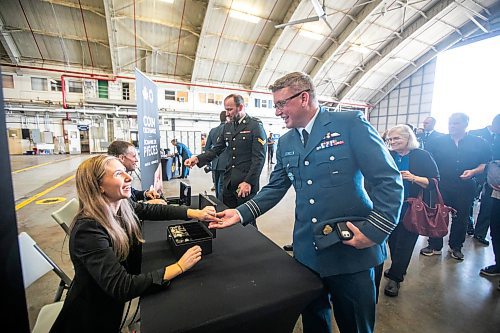 MIKAELA MACKENZIE / WINNIPEG FREE PRESS

Mint employee Karine Verot hands commanding officer Tyler West a special two&#x2011;dollar circulation coin commemorating the 100th anniversary of the Royal Canadian Air Force after the unveiling at 17 Wing on Wednesday, Sept. 18, 2024.

Standup.
Winnipeg Free Press 2024