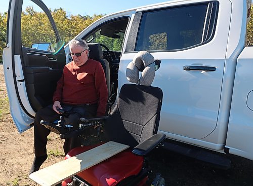 Westman’s Alberto Dallari demonstrates how he lowers and extends the driver's seat to get out of his 2022 white Chevrolet Silverado Trail Boss crew cab and into his wheelchair. Dallari has muscular dystrophy and is unable to walk, but he is able to drive his modified truck using customized hand controls and a ball-shaped knob on the steering wheel. (Michele McDougall/The Brandon Sun)