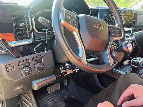 A close-up of Alberto Dallari's steering wheel in his 2022 white Chevrolet Silverado Trail Boss crew cab. The accelerator and brake lever is on the left, and on the steering wheel is a ball-shaped knob to help make steering easier. Dallari has muscular dystrophy and is unable to walk, but he is able to drive his modified truck using the customized hand controls. (Michele McDougall/The Brandon Sun)
