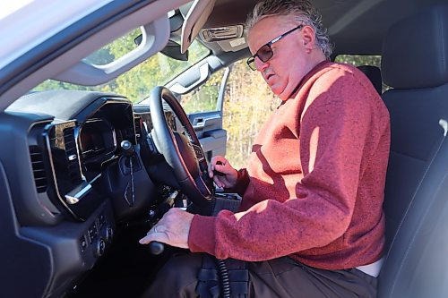 Westman’s Alberto Dallari has his left hand on the accelerator and brake lever, and his right hand is on a ball-shaped knob on the steering wheel of his 2022 white Chevrolet Silverado Trail Boss crew cab and into his wheelchair. Dallari has muscular dystrophy and is unable to walk, but he is able to drive his modified truck using customized hand controls. (Michele McDougall/The Brandon Sun)